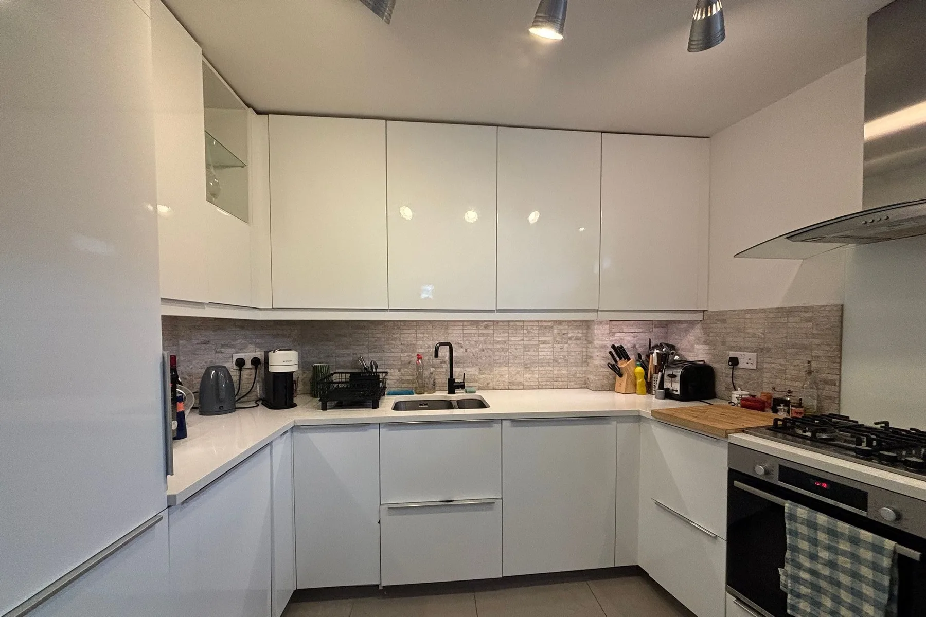 A modern kitchen with white cabinets, a tiled backsplash, and a cooking range.