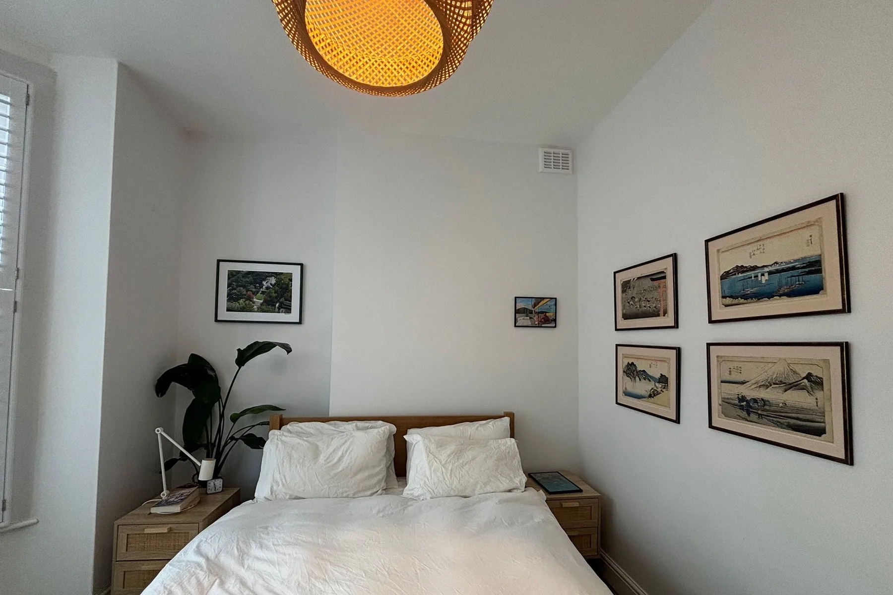 A bedroom with a neatly made bed and framed pictures on the wall.