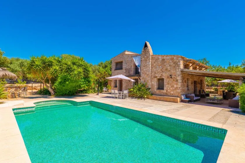 Una piscina al aire libre junto a un edificio de piedra y un patio.