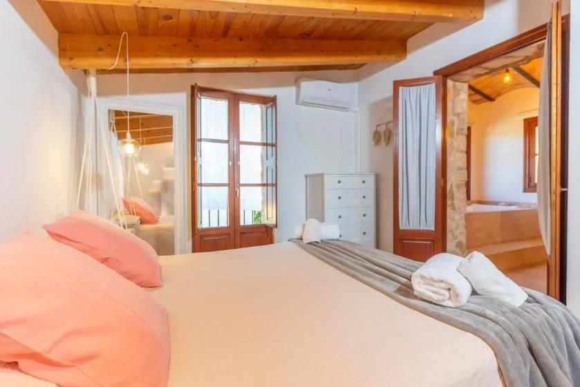 Un dormitorio con una cama, vigas de madera en el techo y una puerta a otra habitación.