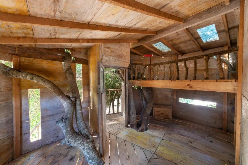 Interior rústico de madera con un altillo elevado y tragaluces en el techo.