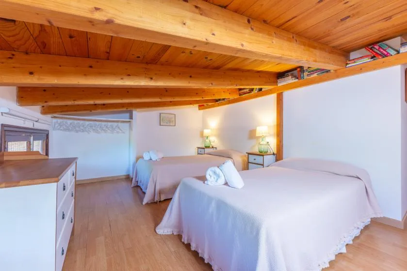 Un dormitorio con dos camas bajo un techo con vigas de madera.