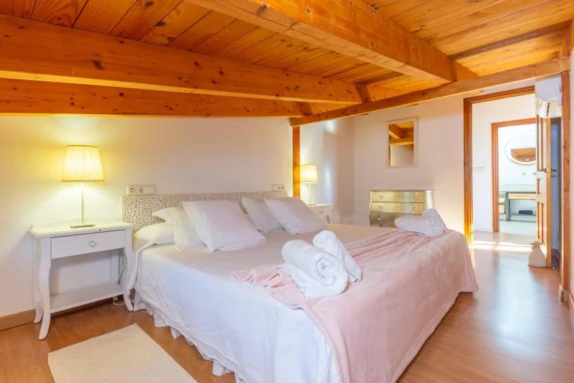 Un dormitorio con una cama grande, mesitas de noche y techo de madera.