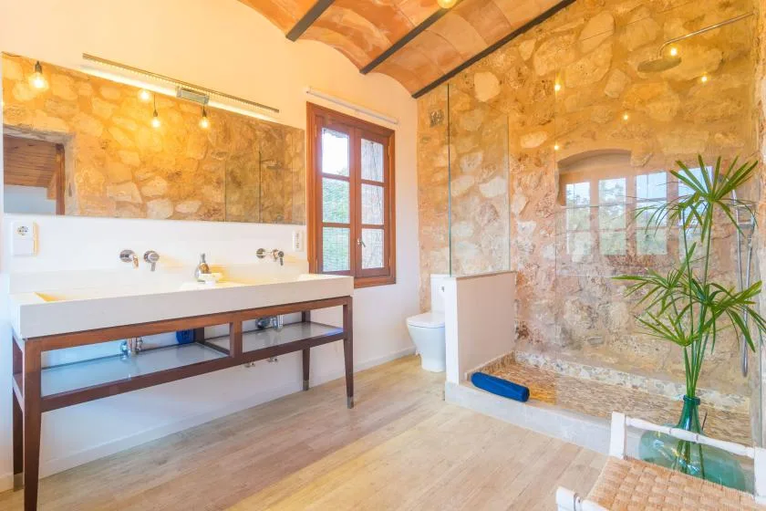 Un baño luminoso con un lavabo largo y una ducha con mampara de vidrio.