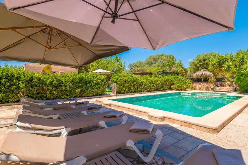 Una piscina al aire libre junto a tumbonas y grandes sombrillas.