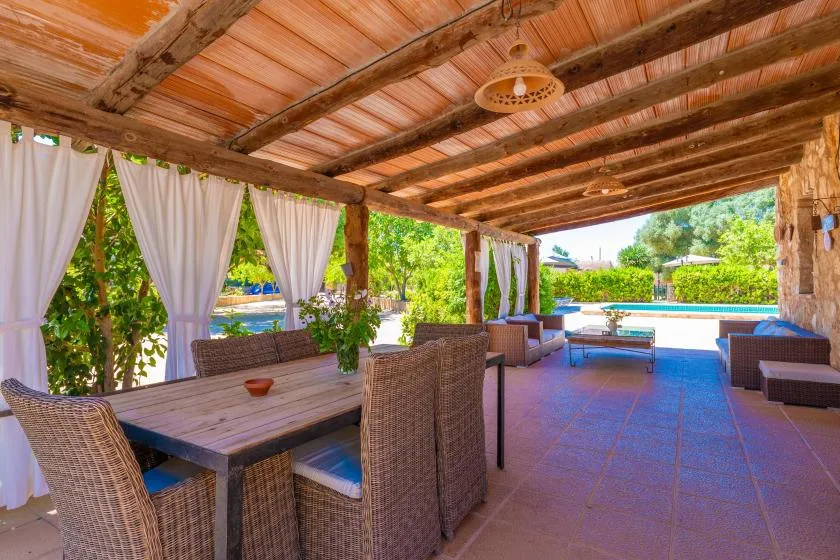 Una zona cubierta de comedor y estar al aire libre da a una piscina.