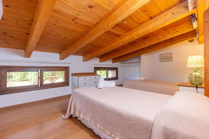 Un dormitorio con camas bajo un techo de madera cálida con vigas expuestas.