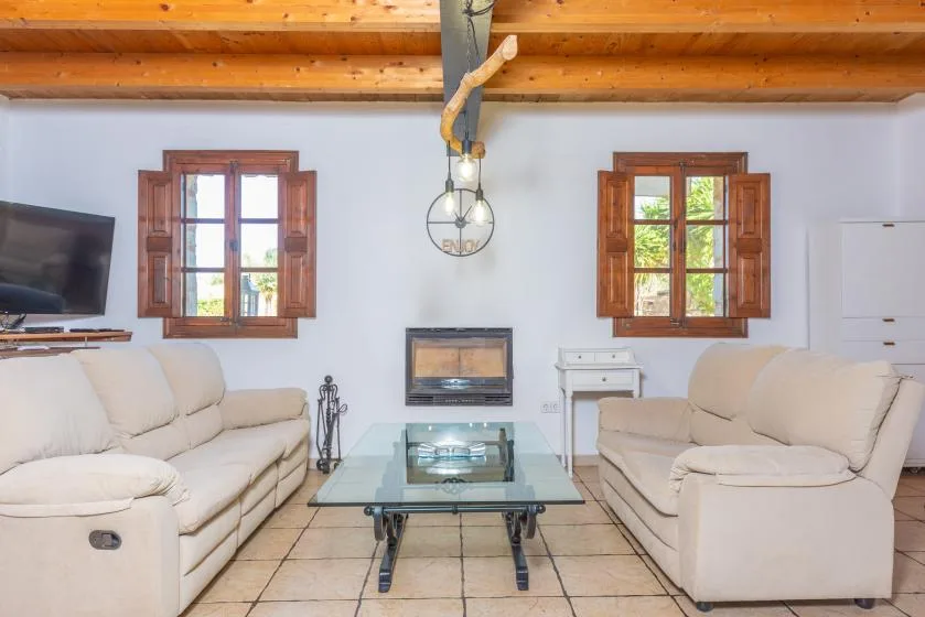 Una sala de estar con asientos tapizados, una mesa de centro de vidrio y una chimenea.