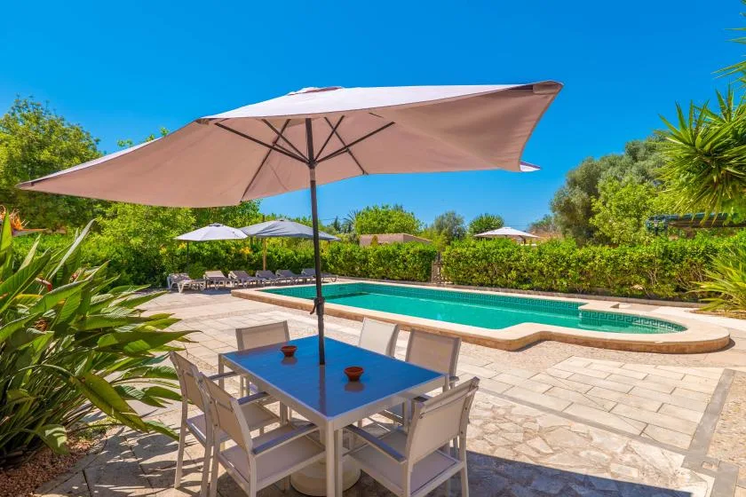 An outdoor pool area with patio seating beneath a large umbrella.