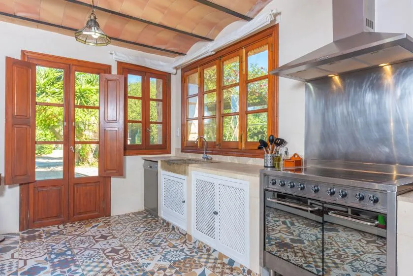 Una cocina luminosa con ventanas de marcos de madera y una estufa de acero inoxidable.