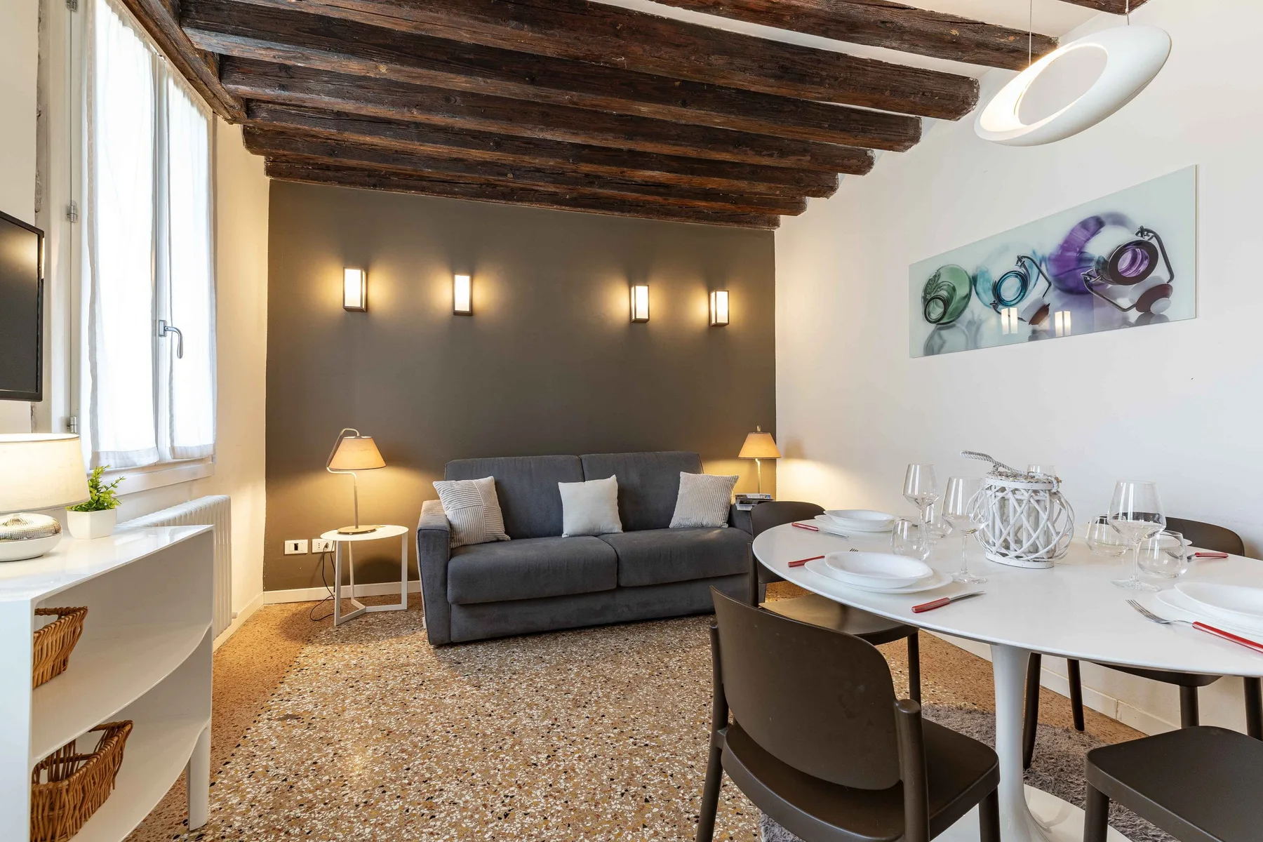 Una sala de estar y comedor con un sofá gris y una mesa puesta.