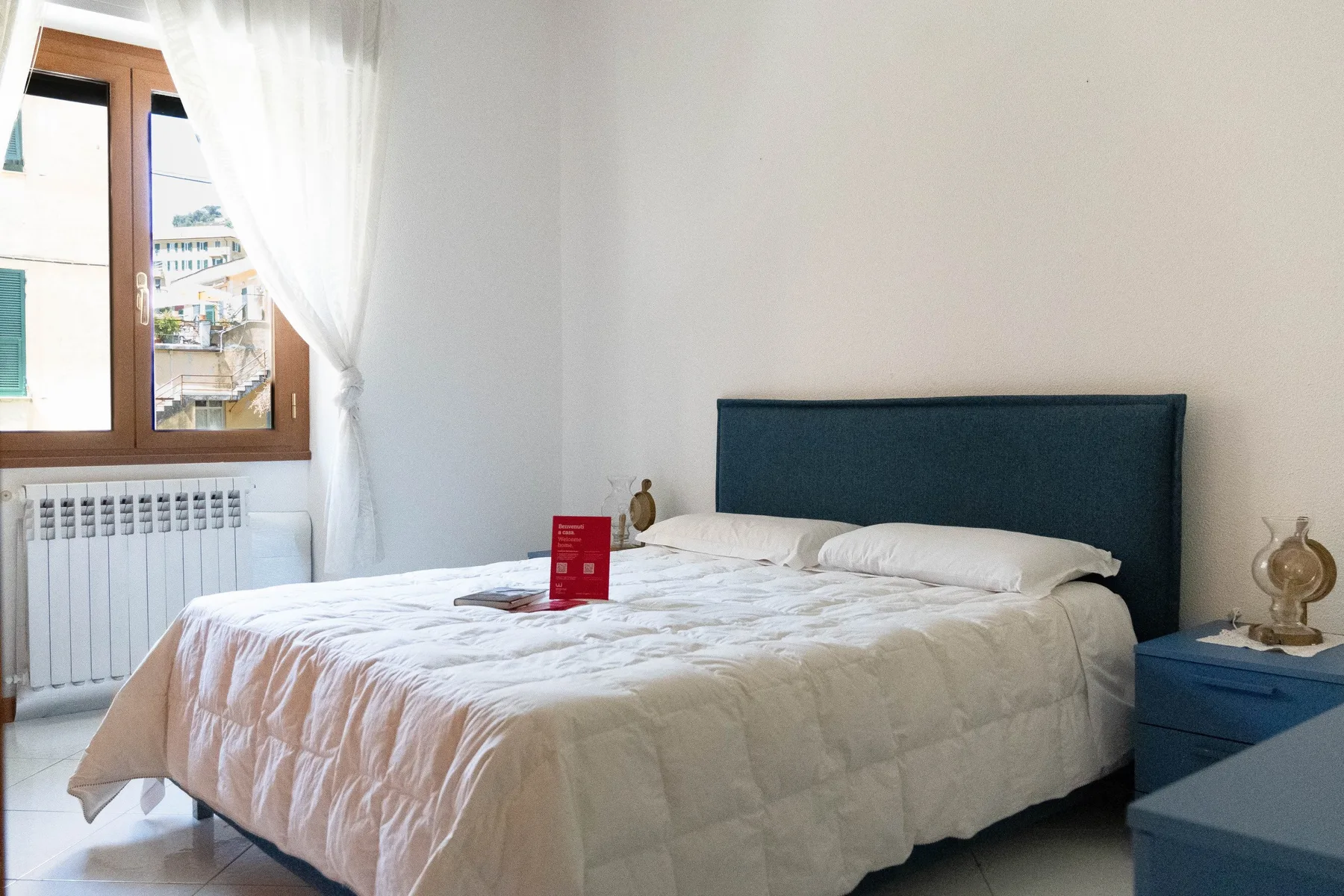 Un dormitorio con una cama bien tendida junto a una ventana.