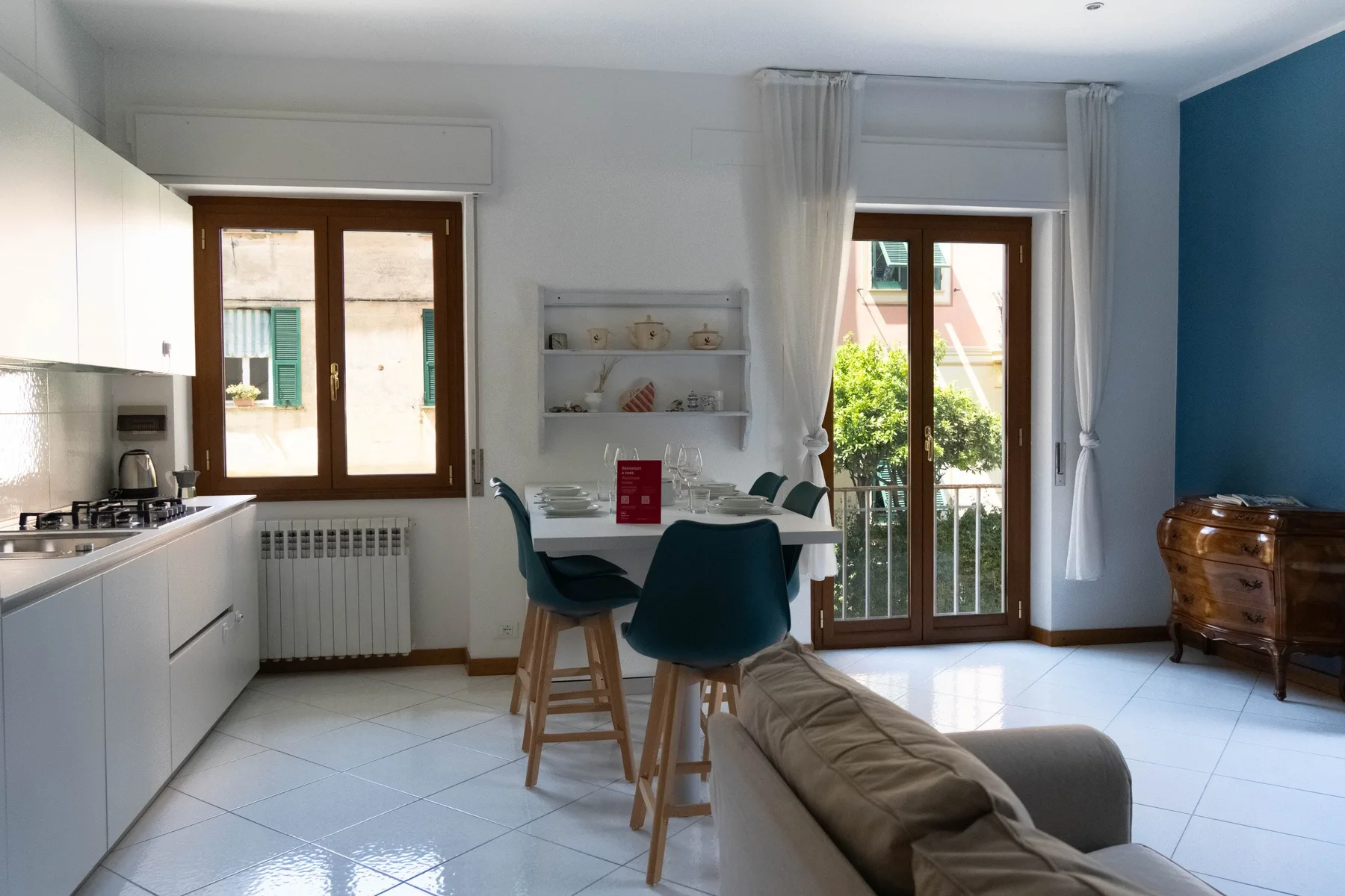 Una luminosa cocina y comedor con una mesa junto a las puertas del balcón.