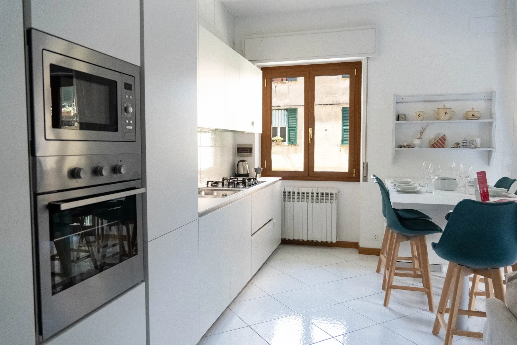 Una luminosa cocina con comedor, armarios blancos y una ventana.