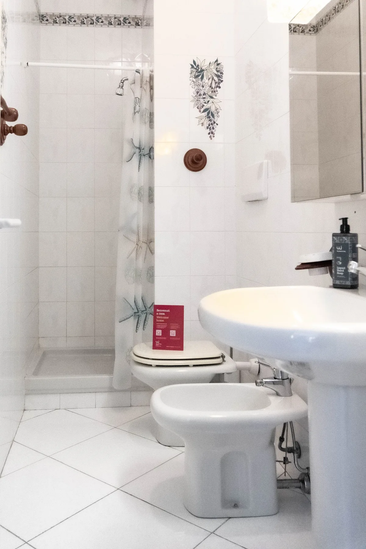 Un baño alicatado con ducha, lavabo e inodoro.