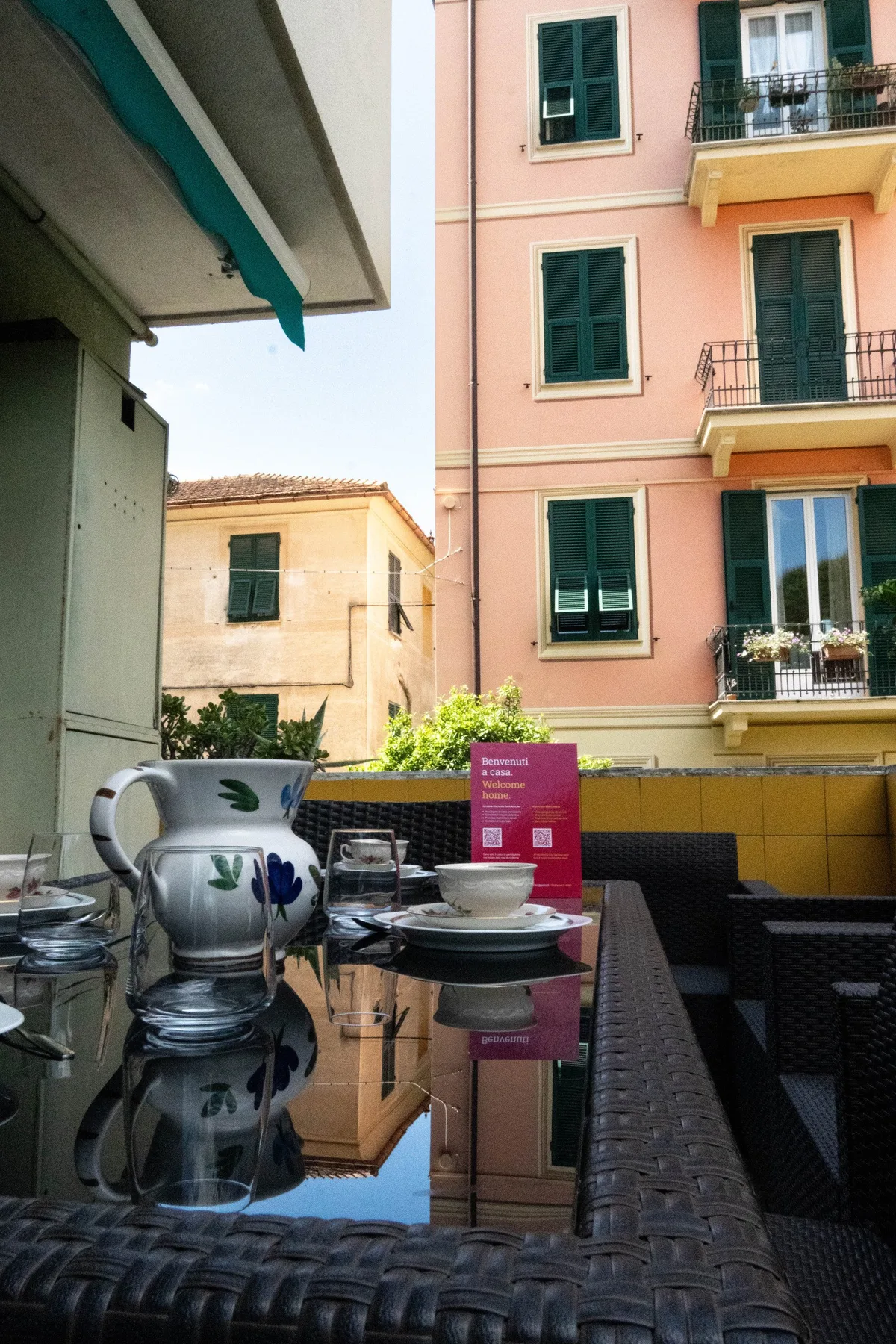 Un comedor en un patio con una mesa reflectante junto a edificios de apartamentos coloridos.