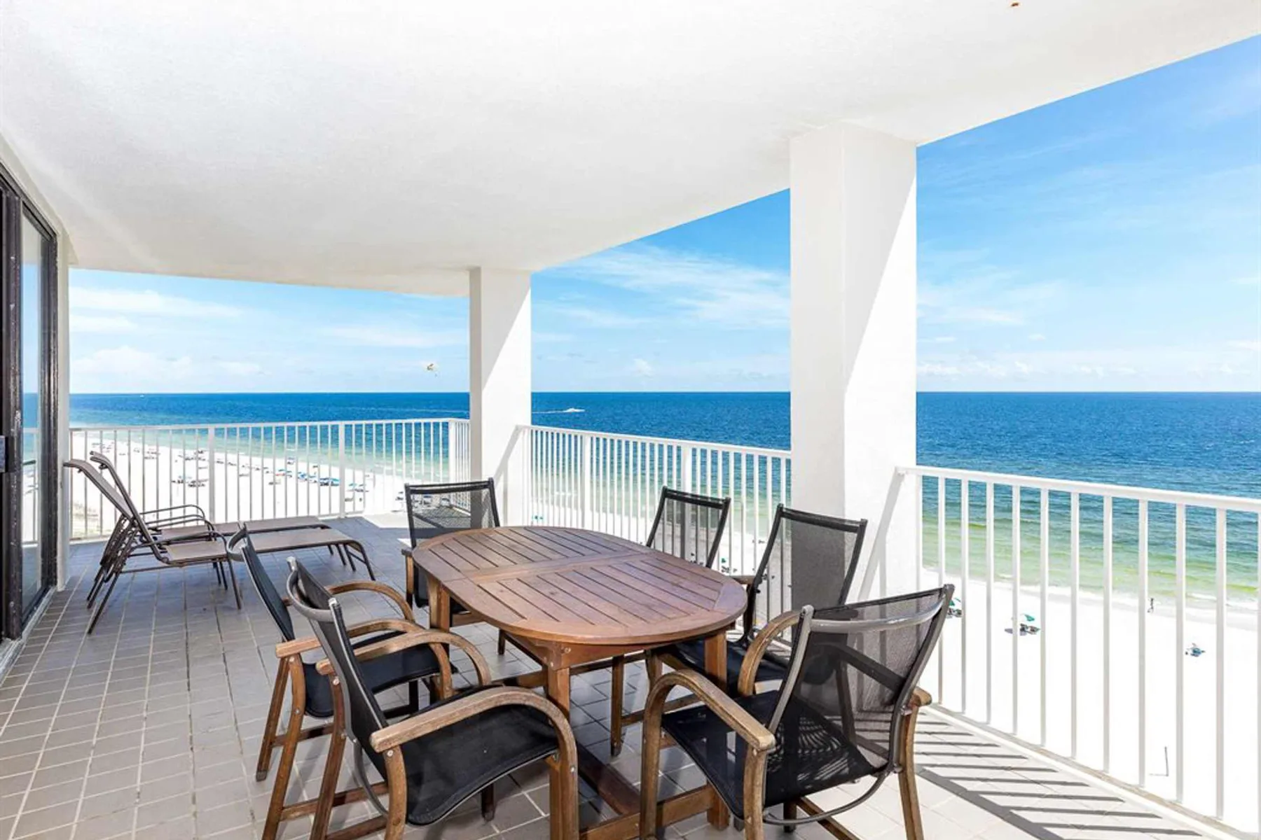 Una terraza cubierta frente al mar tiene una mesa de comedor y asientos con vistas al agua.