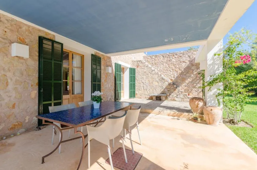 Un patio cubierto con mesa y sillas junto a las paredes de piedra.