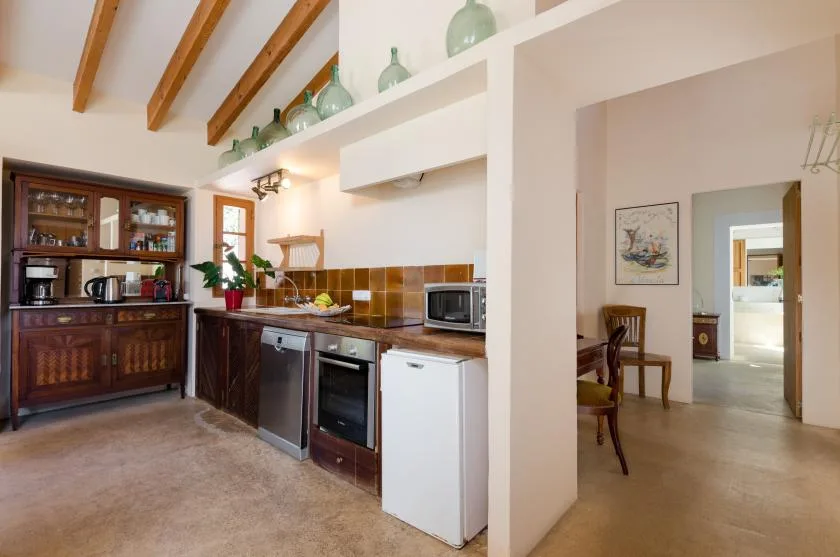 Una cocina con gabinetes de madera oscura, un salpicadero de azulejos y vigas expuestas.