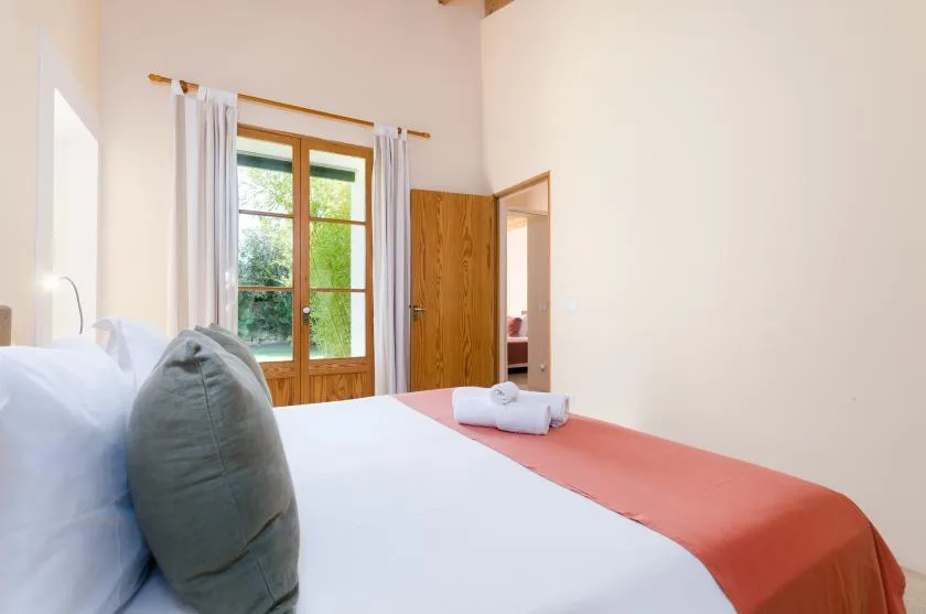 Un dormitorio con una cama bien tendida y una ventana enmarcada por cortinas.