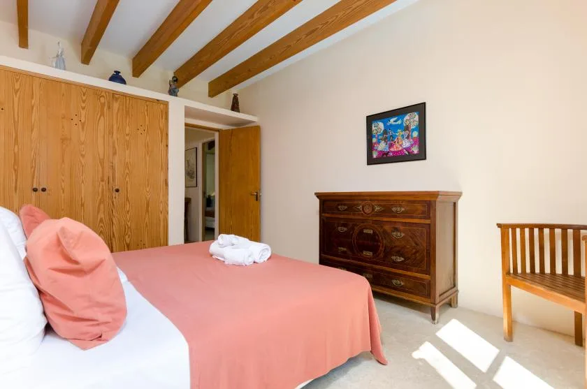 Un dormitorio con una cama, un armario de madera y una cómoda.