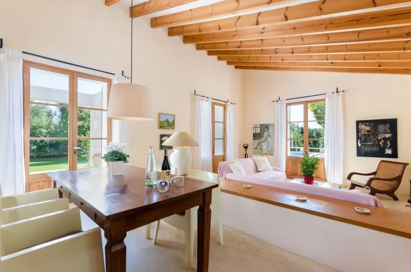 Una luminosa sala de estar y comedor con una mesa de madera y asientos claros.
