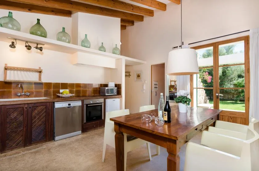 Una cocina y comedor con una mesa de madera junto a grandes ventanas.