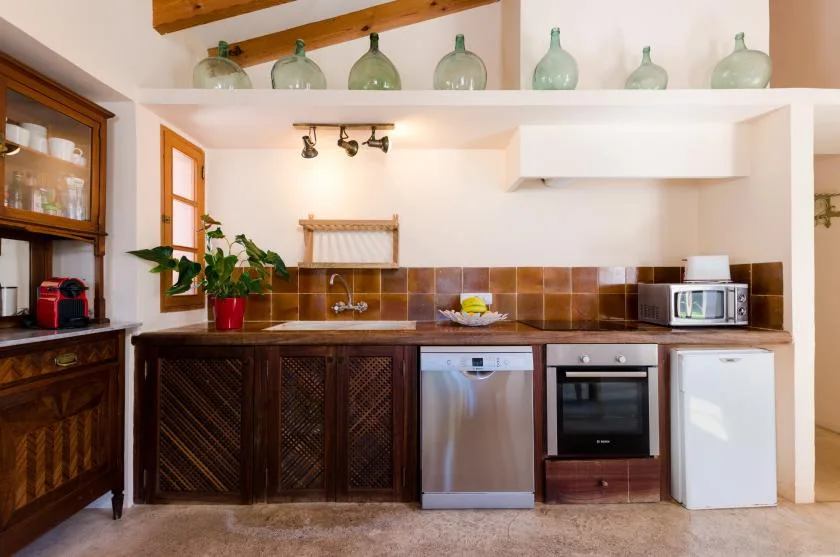Una cocina con gabinetes de madera oscura, un salpicadero de azulejos y electrodomésticos sobre la encimera.