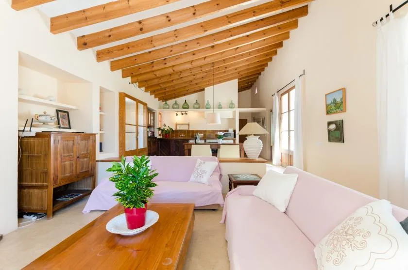 Una sala luminosa con asientos claros, una mesa de centro de madera y vigas expuestas.