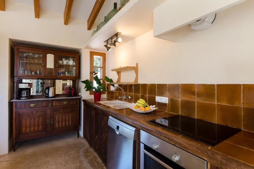 Una cocina con gabinetes de madera oscura, un salpicadero de azulejos y una estufa empotrada.