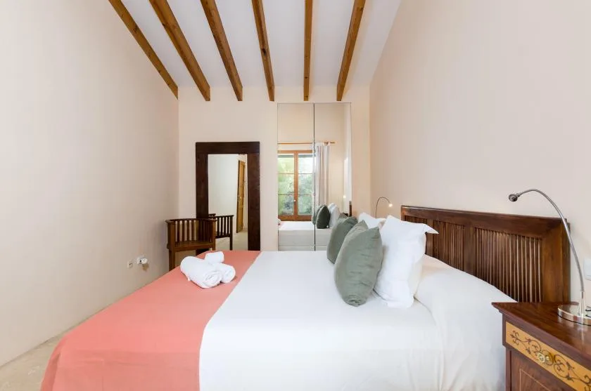 Un dormitorio con una cama bien tendida y vigas de madera a la vista.