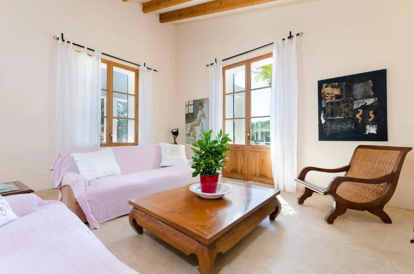 Una sala luminosa con asientos, una mesa de centro de madera y ventanas altas.