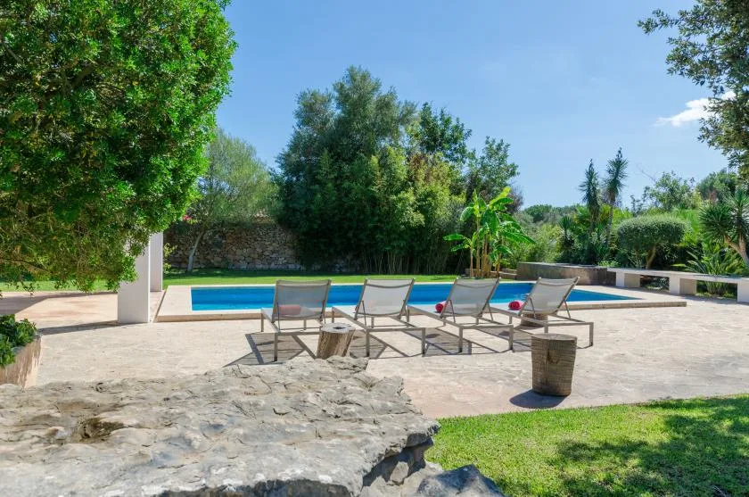 Una piscina al aire libre está rodeada por un patio pavimentado y asientos.