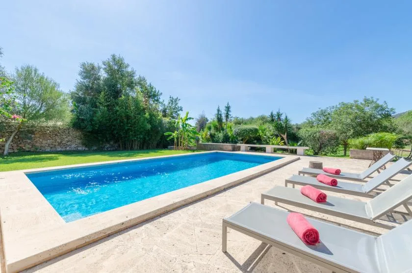 An outdoor swimming pool beside a paved deck with lounge seating.