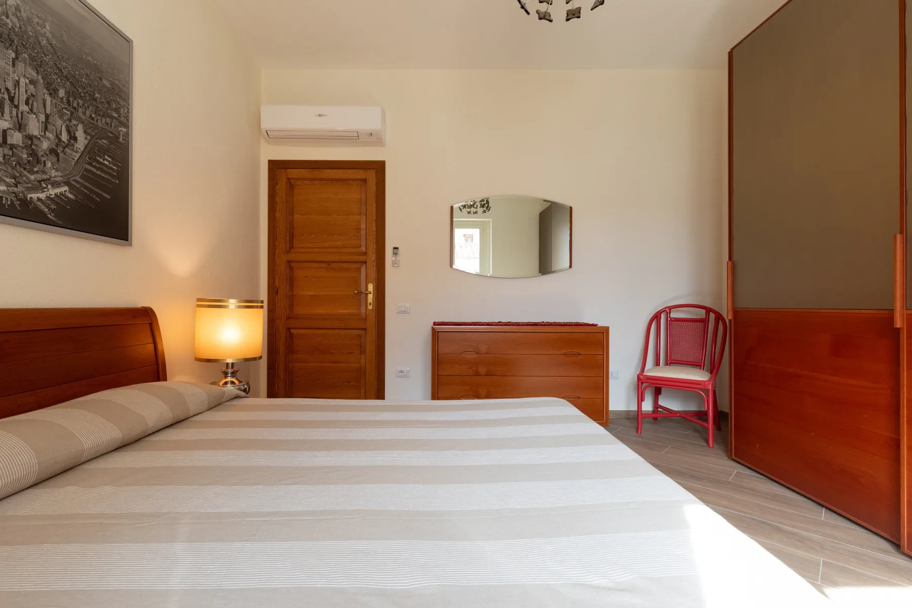 Un dormitorio con una cama, muebles de madera y un espejo en la pared.