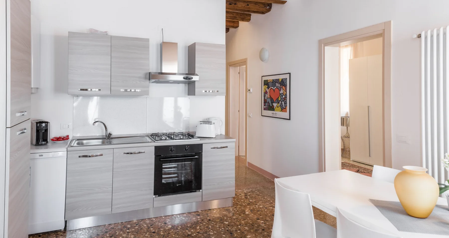 A bright kitchen and dining area with a white table beside the kitchen.