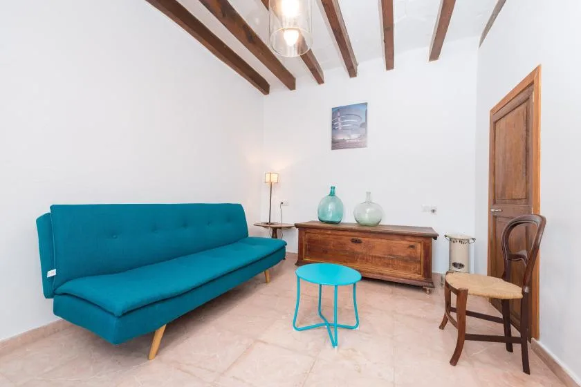 A sitting room with a teal sofa, wooden chest, and small round table.