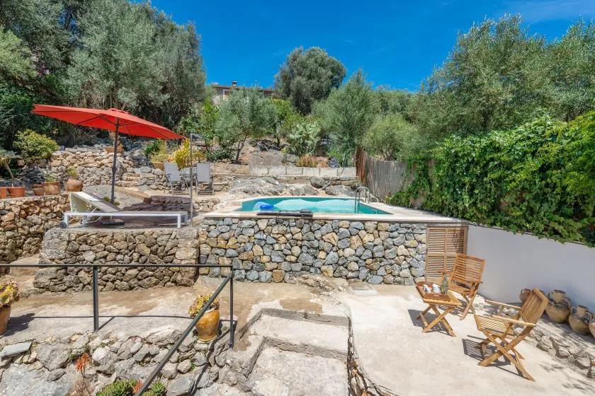 A stone terrace with outdoor seating overlooks a small swimming pool.