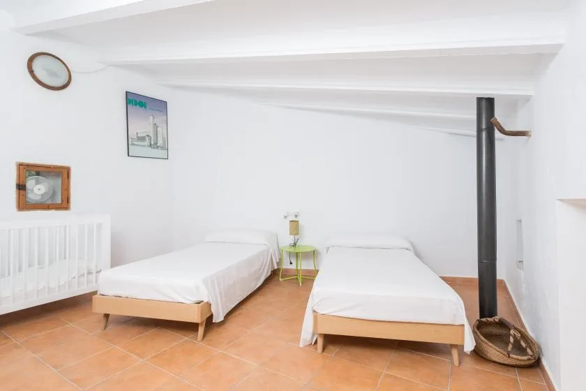 A bright attic bedroom with two beds and a small table between them.