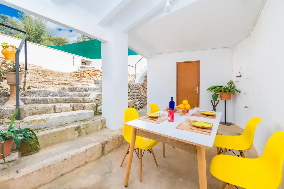 A dining area with a table and bright yellow seating beside outdoor stone steps.