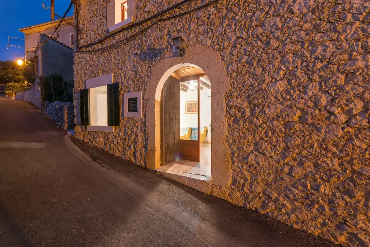A stone building entrance opens onto a narrow street at dusk.