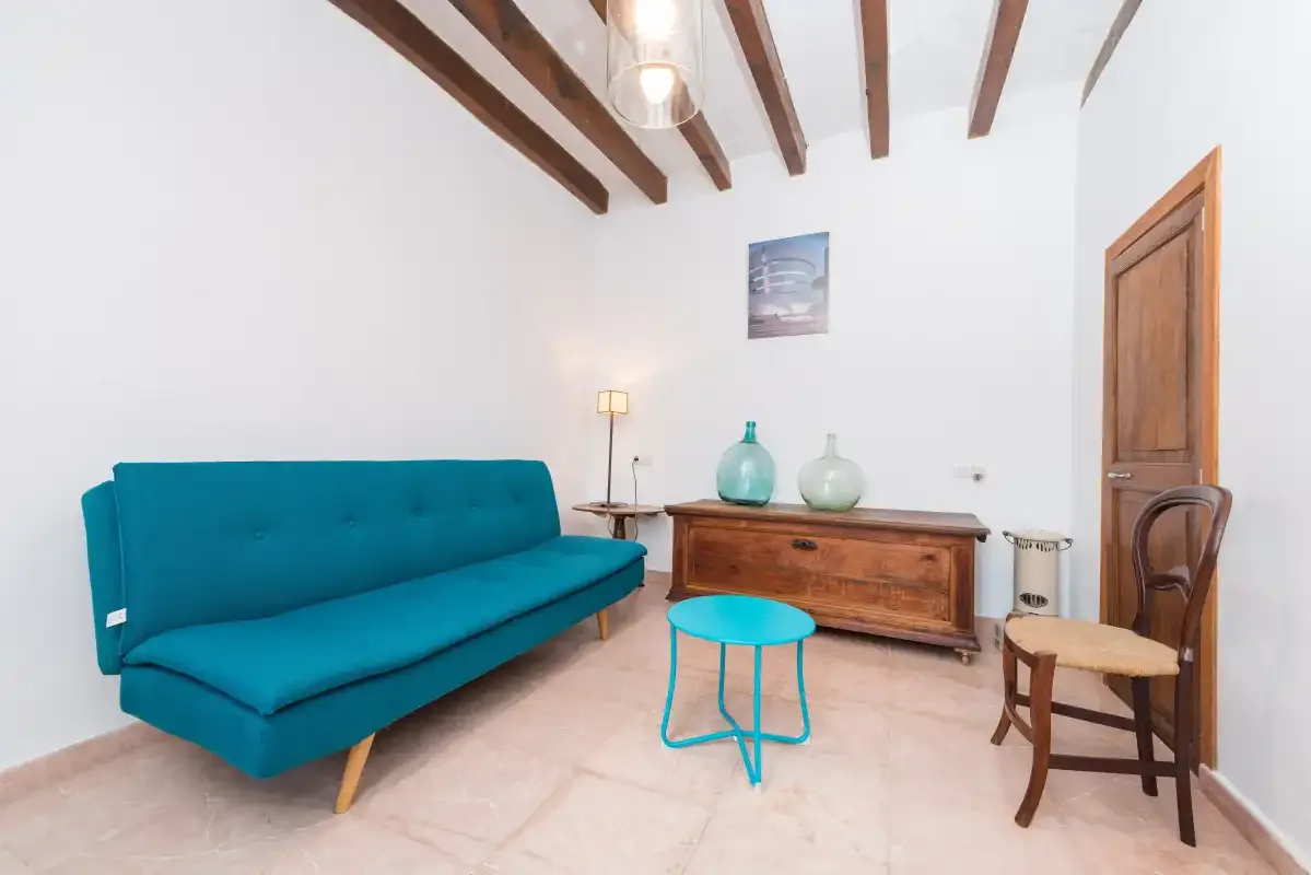 A bright living room with a teal sofa and wooden furniture.