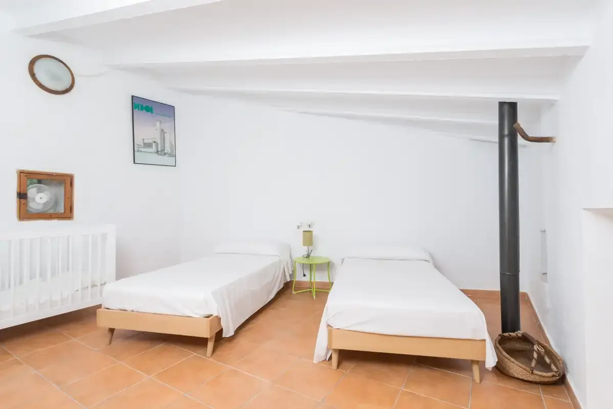 A bright bedroom with two beds and white bedding.