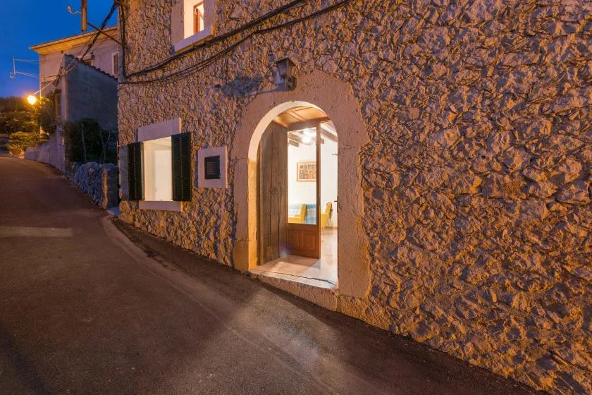 A stone building entrance opens onto a narrow street at dusk.