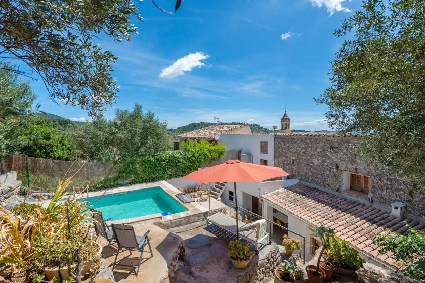 A courtyard pool sits beside tiled-roof buildings, with trees surrounding the patio.