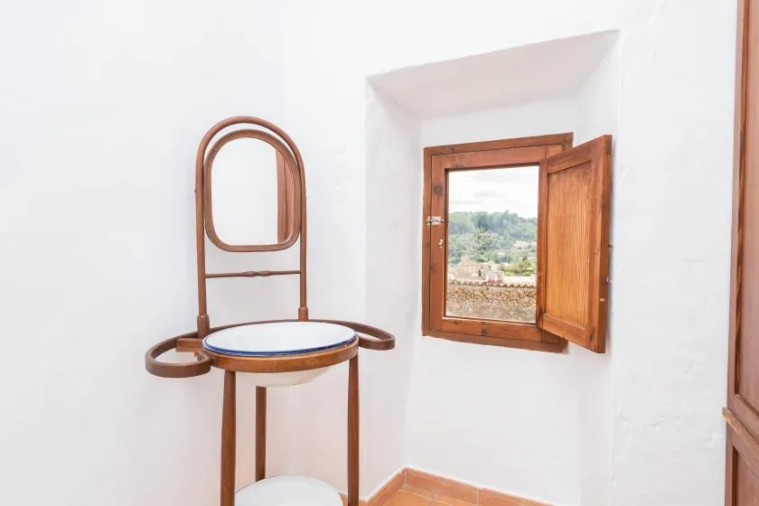A bright white room with a wooden chair beside an open window.