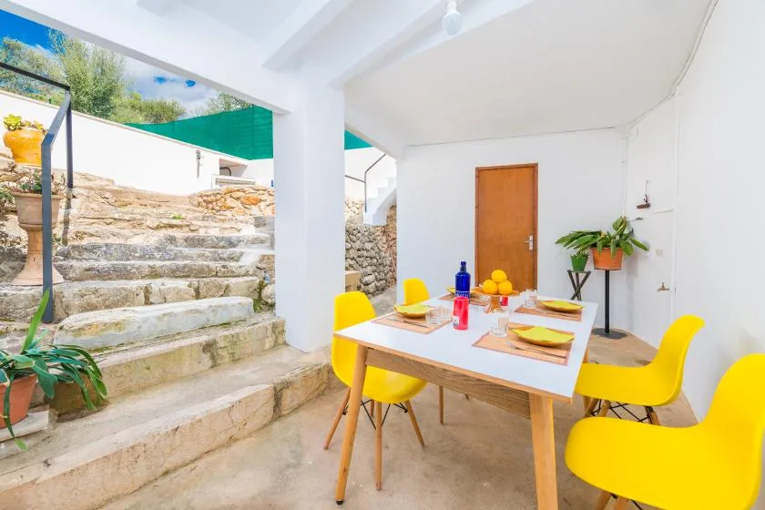 A bright dining area with a table and yellow seating beside stone steps.
