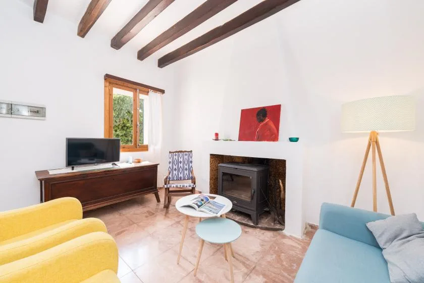A bright living room with exposed ceiling beams and a fireplace.
