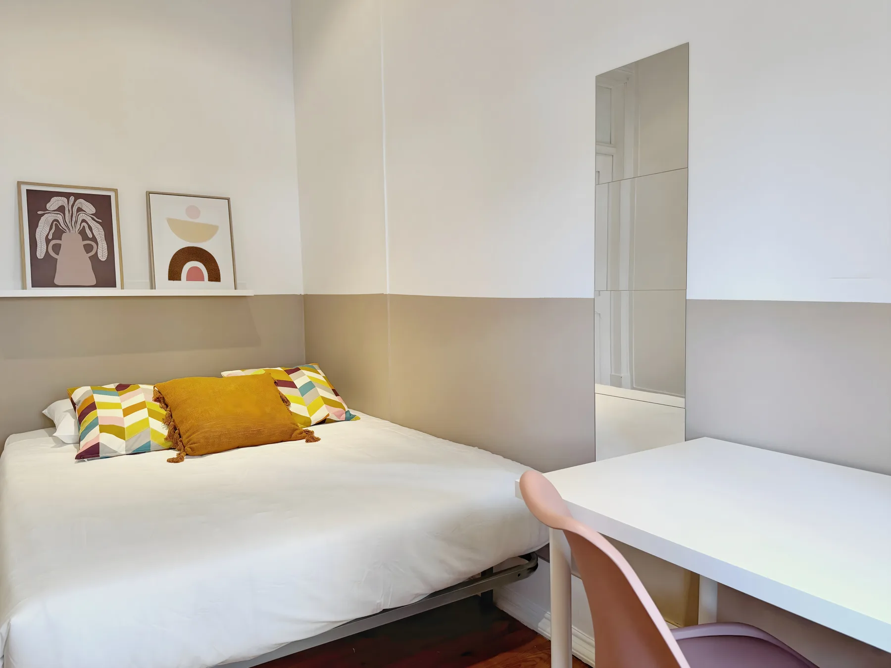 A bedroom with a bed and a white desk beside it.