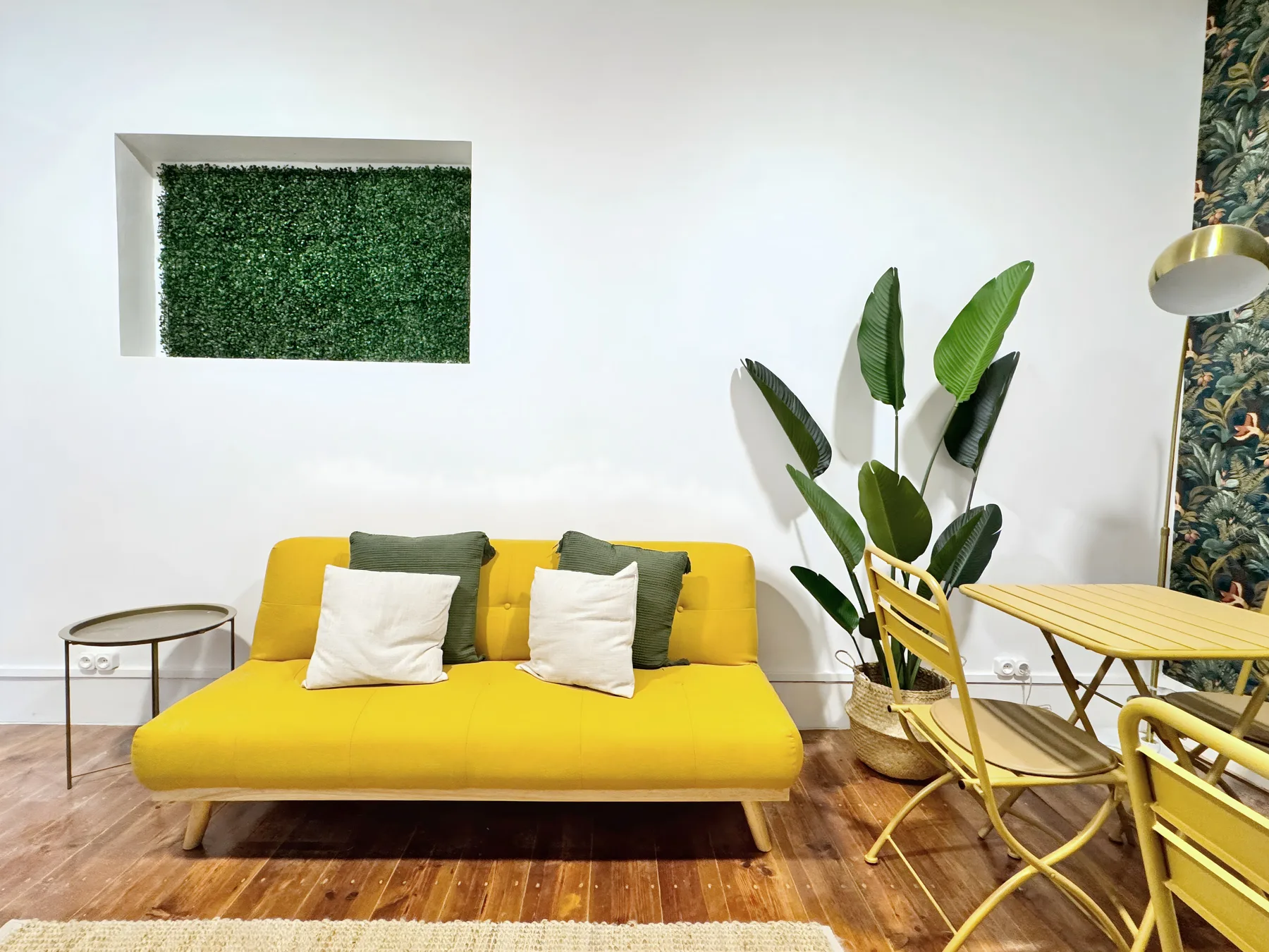 A bright living area with yellow seating, a dining table, and a leafy plant.